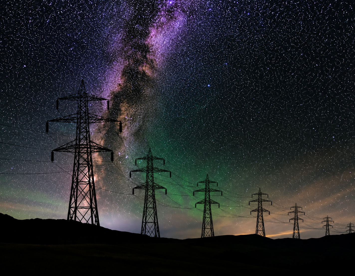 Line of transmission pylons silhouetted against a star-filled night sky