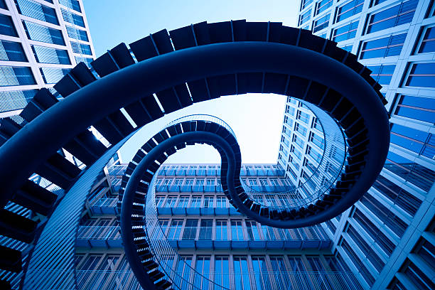 Spiral staircase sculpture framed by blue glass office buildings