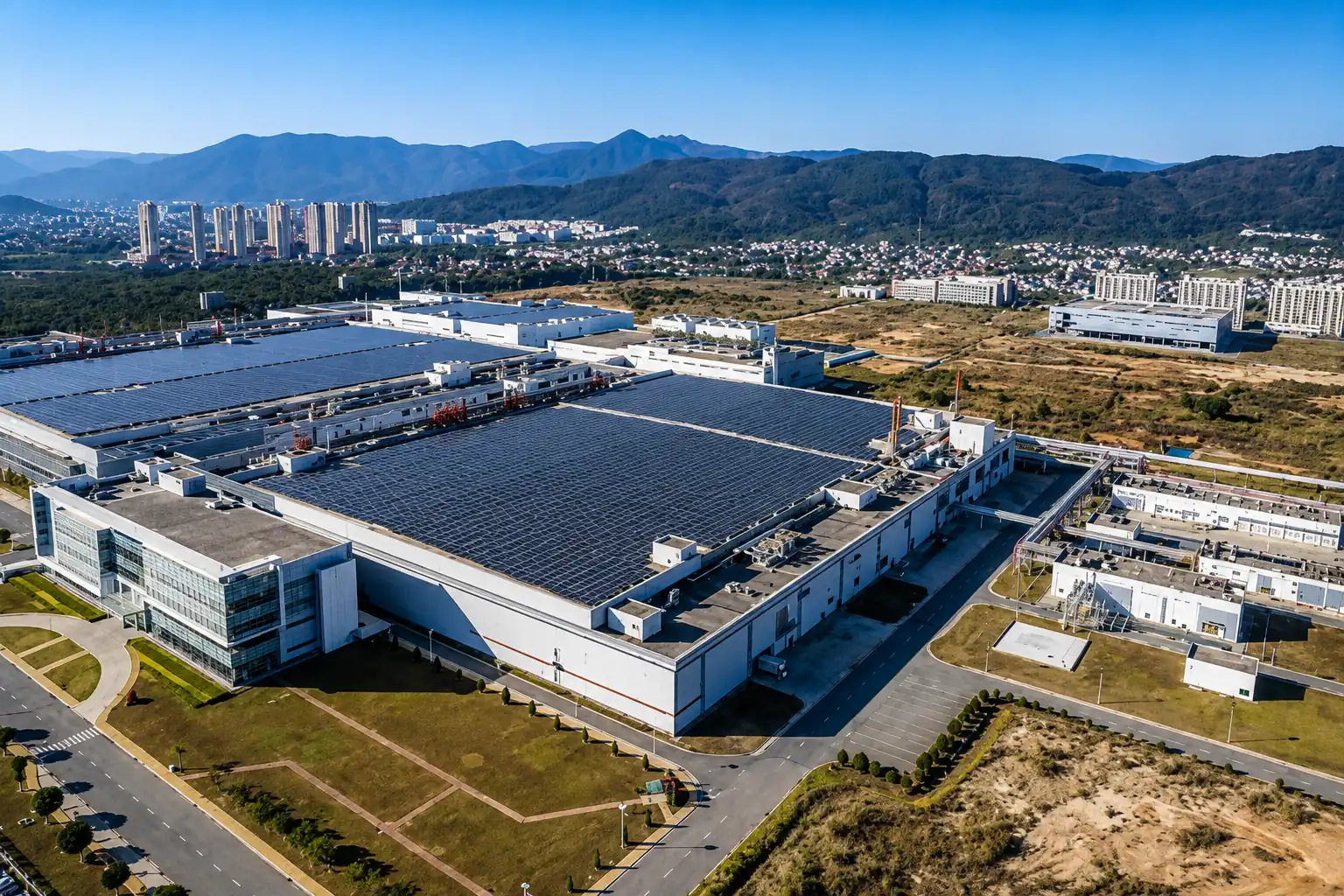 Aerial view of a large manufacturing facility with solar panels covering its roof