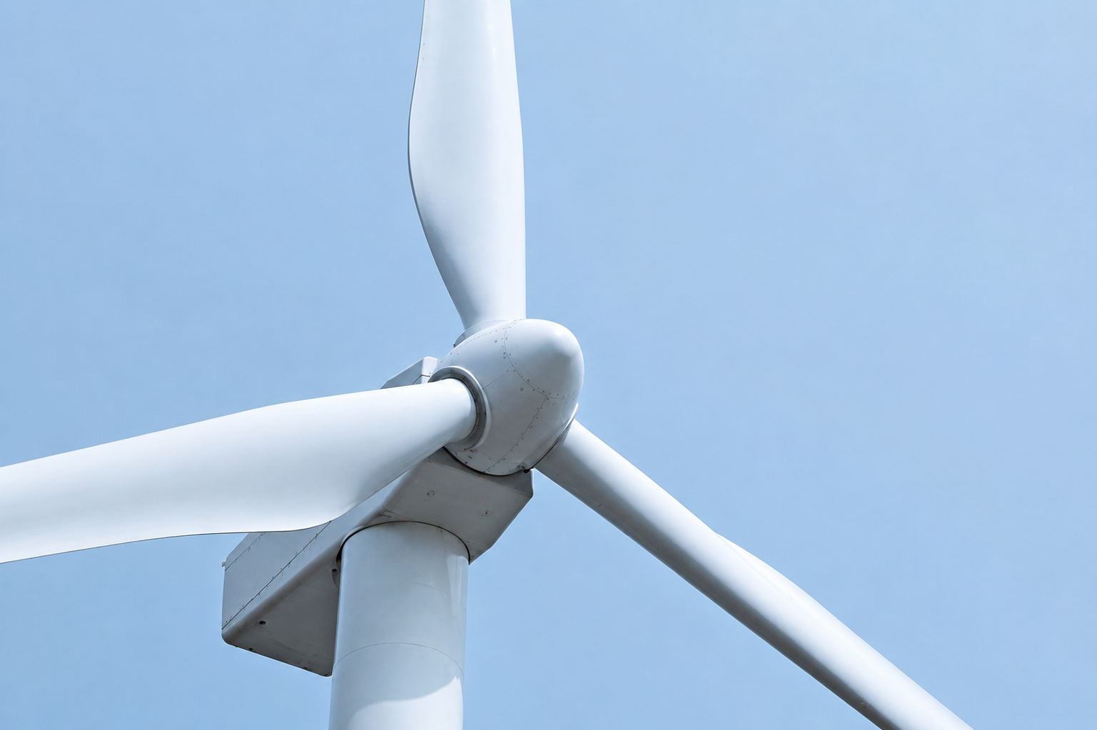 Close-up of a wind turbine hub and blades against the sky